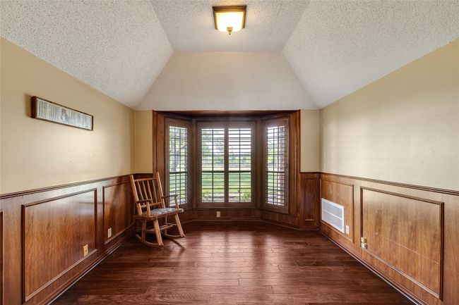 Unfurnished room featuring a wainscoted wall, dark wood-type flooring, lofted ceiling, and a textured ceiling | Image 10