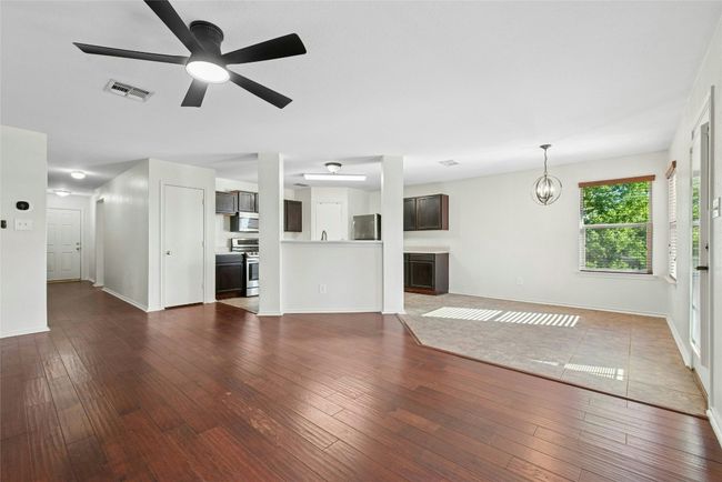 Unfurnished living room with a ceiling fan, dark wood-type flooring, and a chandelier | Image 6