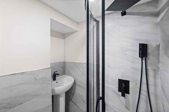 Full bath featuring a marble finish shower, tile walls, and wainscoting | Image 20