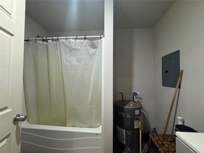 Bathroom featuring water heater, shower / bathtub combination with curtain, electric panel, and vanity | Image 13