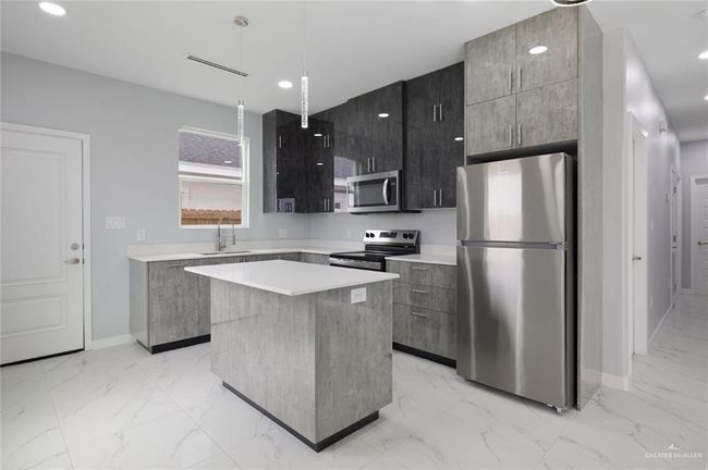 Kitchen with appliances with stainless steel finishes, modern cabinets, light marble finish flooring, a center island, and recessed lighting | Image 6
