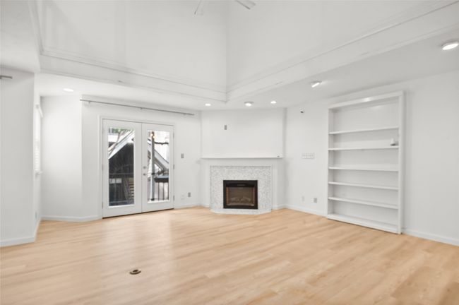 Unfurnished living room with french doors, recessed lighting, light wood-type flooring, baseboards, and a tile fireplace | Image 5