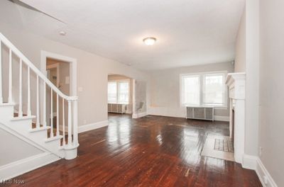 Unfurnished living room featuring dark wood-type flooring and radiator heating unit | Image 3