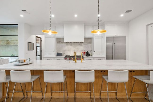Kitchen featuring stainless steel built in refrigerator, white cabinets, a spacious island, premium range hood, and decorative backsplash | Image 16