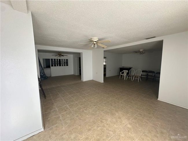 Unfurnished living room featuring a textured ceiling and ceiling fan | Image 8