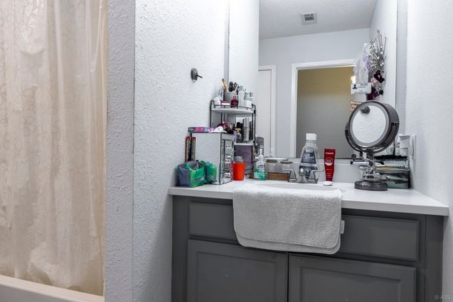 Bathroom with vanity, a textured wall, and shower / tub combo | Image 10