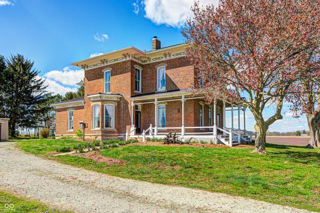 italianate-style house with brick siding, a porch, a chimney, and a front lawn | Image 7