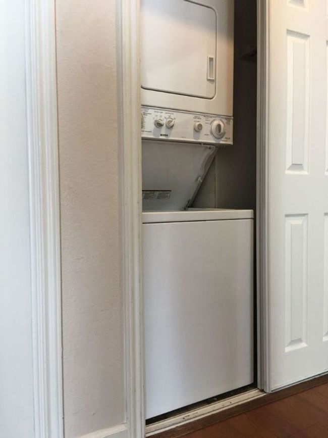Laundry area featuring stacked washer and clothes dryer, dark wood finished floors, and laundry area | Image 14