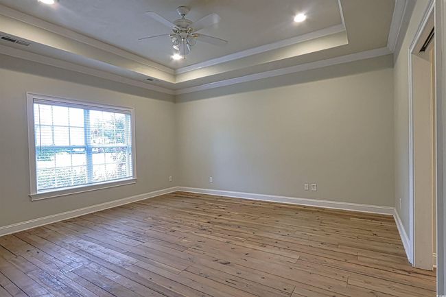 Empty room featuring a raised ceiling, ornamental molding, light wood-style floors, ceiling fan, and recessed lighting | Image 10