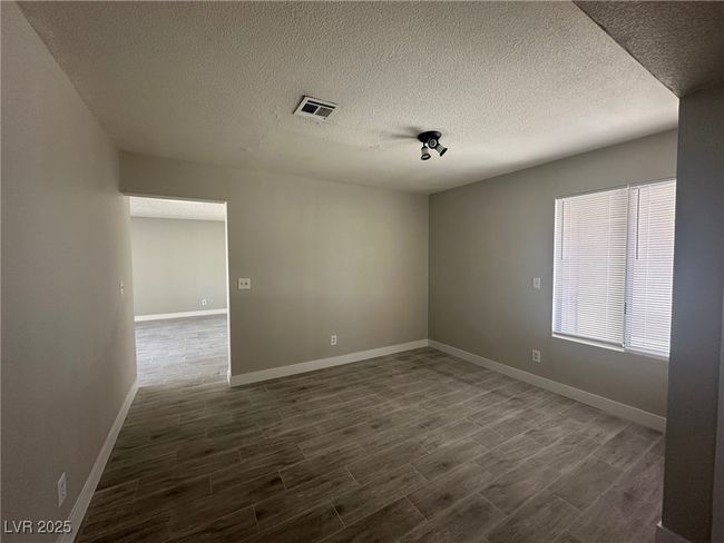 Empty room featuring dark wood-type flooring, a textured ceiling, and baseboards | Image 4