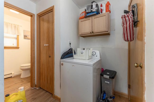 Washroom featuring washer / clothes dryer, baseboard heating, cabinet space, and wood finished floors | Image 31