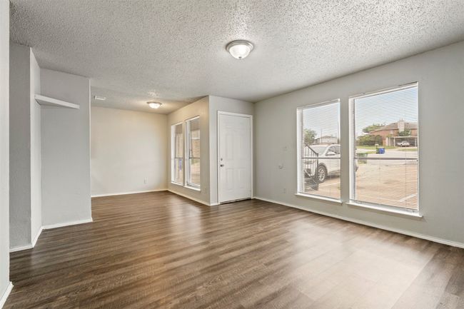 Unfurnished room with wood finished floors, plenty of natural light, a textured ceiling, and baseboards | Image 5