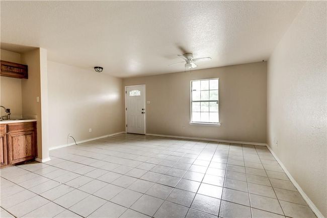Unfurnished living room with a ceiling fan, light tile patterned floors, and a textured ceiling | Image 9
