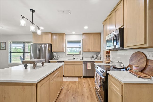 Kitchen with appliances with stainless steel finishes, light brown cabinetry, plenty of natural light, light wood-style flooring, and recessed lighting | Image 15