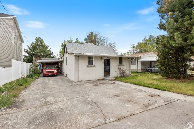 View of front facade with a front lawn, a carport, concrete driveway, fence, and stucco siding | Image 23