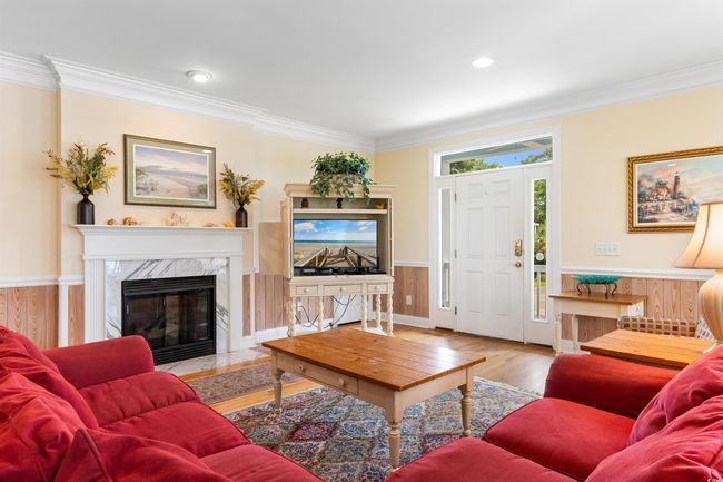 Living room featuring crown molding, wood finished floors, a fireplace, and wainscoting | Image 12