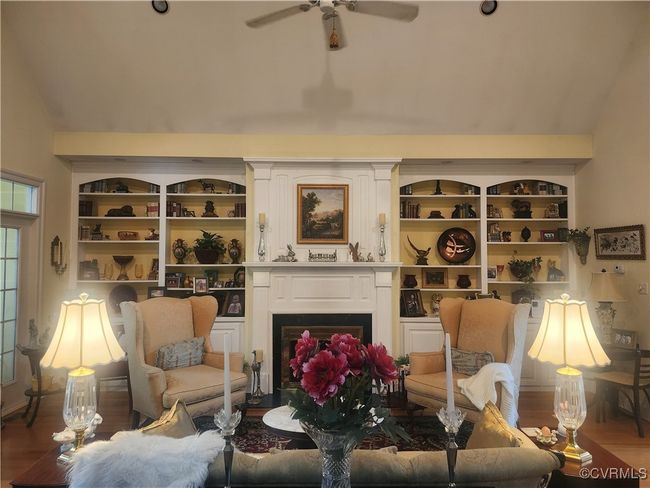 Living area with a fireplace with flush hearth, vaulted ceiling, a ceiling fan, and wood finished floors | Image 5