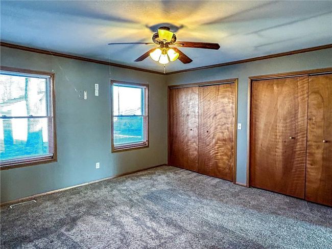 Unfurnished bedroom featuring carpet, crown molding, visible vents, and multiple closets | Image 12