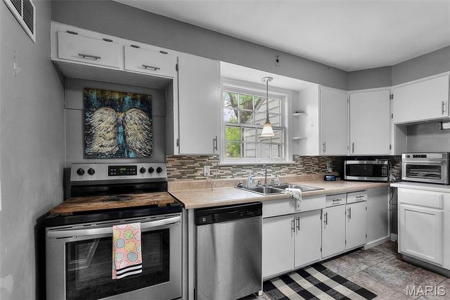 Kitchen featuring a sink, visible vents, white cabinetry, light countertops, and appliances with stainless steel finishes | Image 9