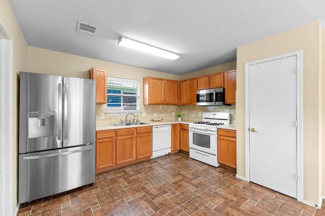 Kitchen with stainless steel appliances, light countertops, tasteful backsplash, and stone finish flooring | Image 17