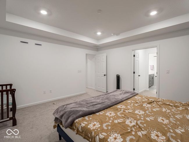 bedroom featuring baseboards, light carpet, recessed lighting, visible vents, and a tray ceiling | Image 34
