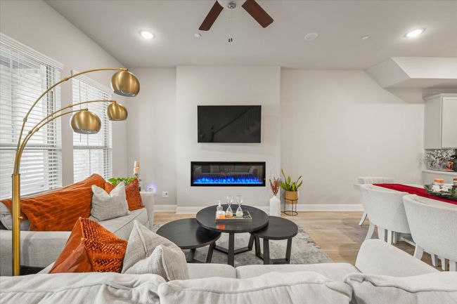 Living room featuring ceiling fan, light wood-style floors, a glass covered fireplace, and recessed lighting | Image 11