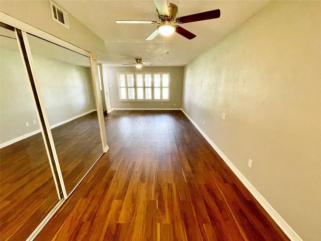 Unfurnished bedroom featuring a ceiling fan, wood finished floors, a closet, baseboards, and visible vents | Image 24