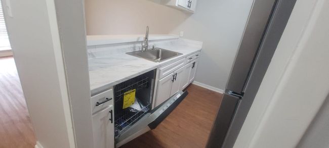 Indoor wet bar with freestanding refrigerator, black dishwasher, and wood finished floors | Image 19