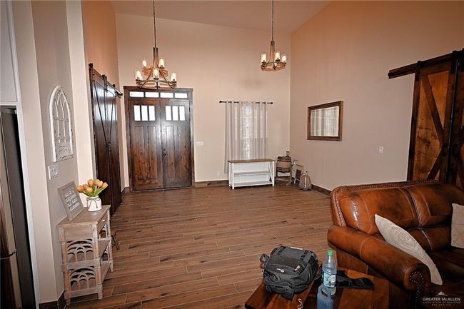 Living room featuring dark hardwood / wood-style floors, a barn door, an inviting chandelier, and high vaulted ceiling | Image 12