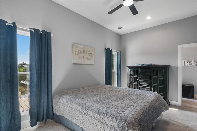 Spacious primary bedroom with abundant natural light, modern ceiling fan, and serene views. | Image 10