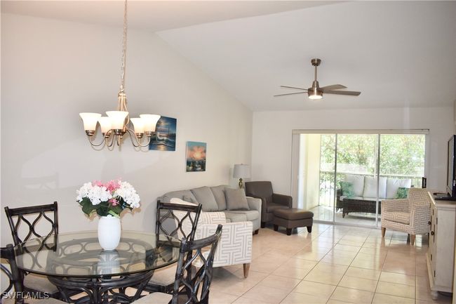 Living room with light tile, ceiling fan with notable chandelier, and high vaulted ceiling | Image 5