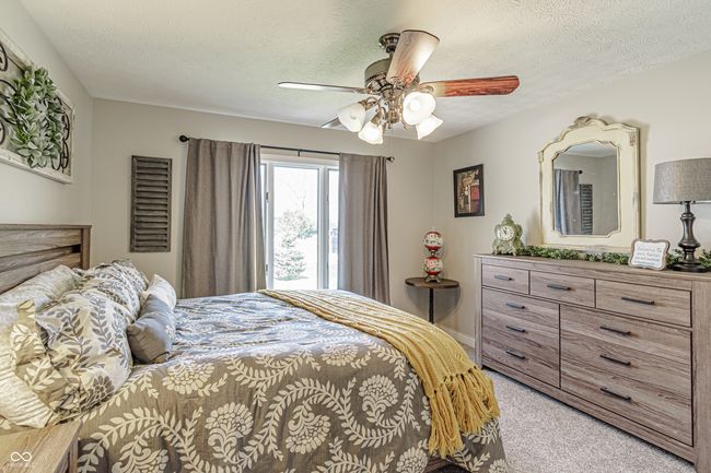 bedroom with light colored carpet, ceiling fan, and a textured ceiling | Image 19