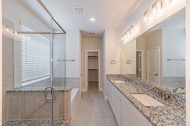 Full bath featuring a shower stall, double vanity, tile patterned floors, a spacious closet, and a bathtub | Image 25