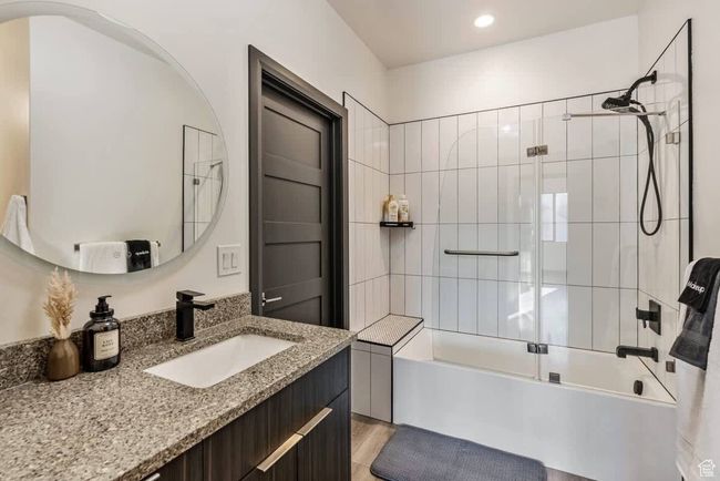 Full bathroom with combined bath / shower with glass door, wood finished floors, and vanity | Image 42
