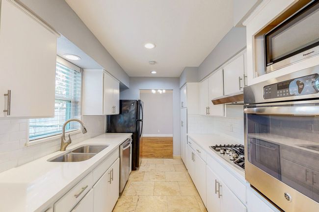 Kitchen featuring quartz countertops, stainless steel appliances, double sink and under cabinet six burner range with a heavy duty vent a hood | Image 19