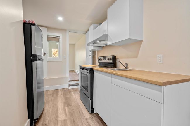 Kitchen featuring white cabinets, under cabinet range hood, stainless steel appliances, and light wood-style floors | Image 15