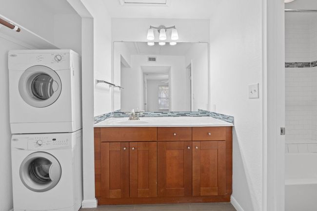 Laundry area featuring laundry area, stacked washer / dryer, visible vents, and a sink | Image 5