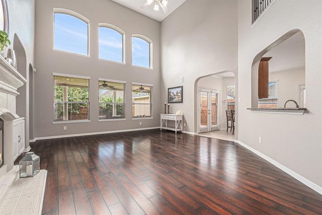 A 2-story family room with a wall of windows allows in a ton of natural light! Arched windows and walkways add to the architectural details in this home that are oh so inviting! This space calls for evenings curled up on the couch chatting about your day with family! | Image 7