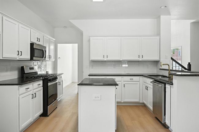 Kitchen featuring stainless steel appliances, tasteful backsplash, a kitchen island, and light wood finished floors | Image 5