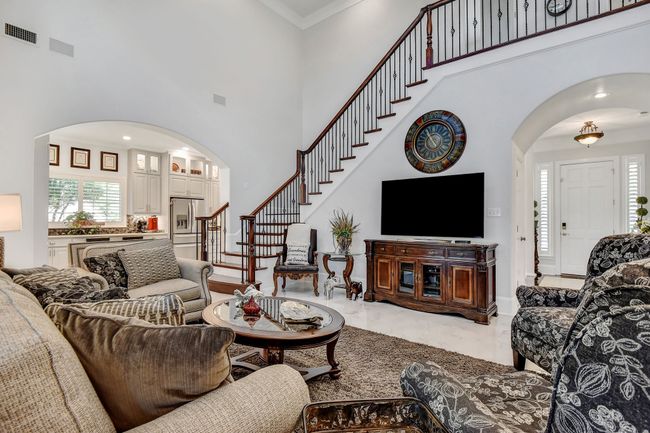 Living room with arched walkways, a high ceiling, marble finish flooring, stairs, and ornamental molding | Image 9