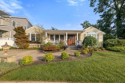 Ranch-style house featuring covered porch and a front lawn | Image 1