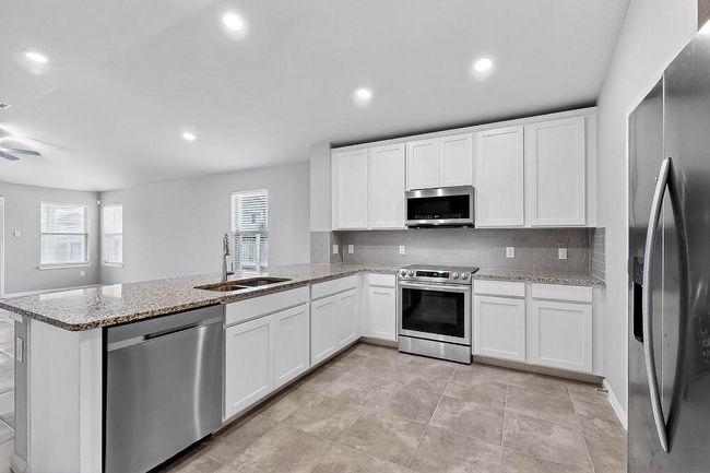 Kitchen with appliances with stainless steel finishes, a peninsula, plenty of natural light, white cabinets, and recessed lighting | Image 11