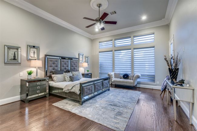 Tucked away to the left side of the home is the spacious primary suite, a tranquil, quite retreat to call your own. With hardwood flooring, custom automated Hunter Douglas shades, and your own door leading privately to the back yard. | Image 17