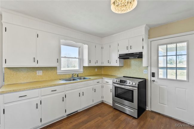 Kitchen featuring a sink, tasteful backsplash, stainless steel electric range, under cabinet range hood, and dark wood-style flooring | Image 8