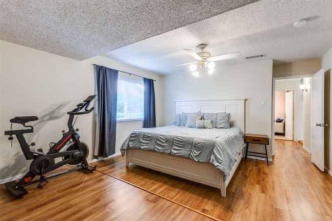 Bedroom featuring light wood-type flooring, a textured ceiling, and a ceiling fan | Image 11