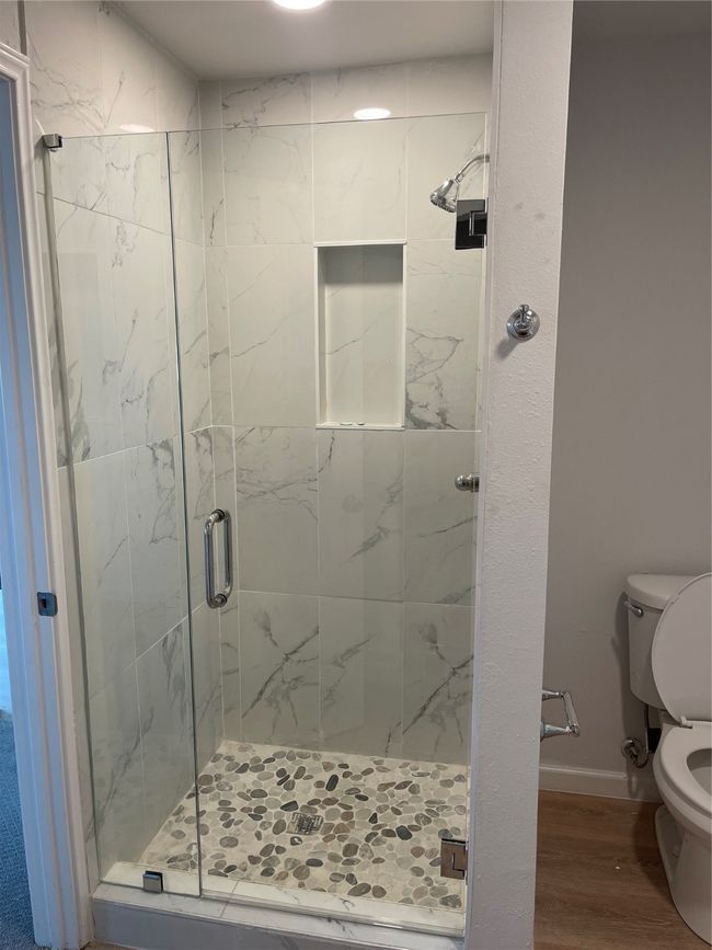 Bathroom featuring a stall shower, baseboards, wood finished floors, and toilet | Image 7