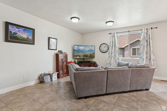 Living room featuring baseboards, light tile patterned floors, and a textured ceiling | Image 7