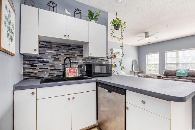 Kitchen with dishwasher, a sink, black microwave, a peninsula, and tasteful backsplash | Image 5
