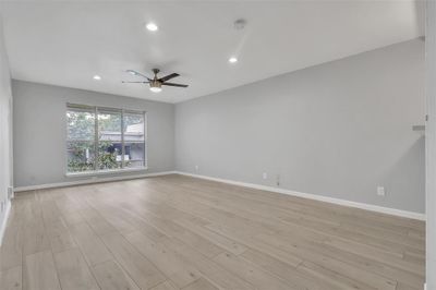 Empty room with ceiling fan and light wood-type flooring | Image 3