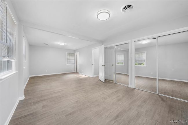 Unfurnished bedroom with visible vents, multiple closets, light wood-type flooring, and baseboards | Image 17